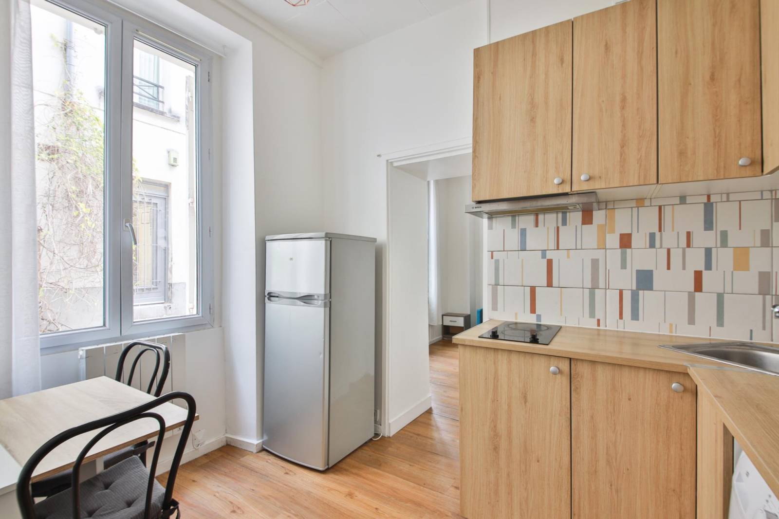 Cuisine aménagée et équipée ouverte sur le séjour dans un appartement 2 pièces à Paris 14ème
