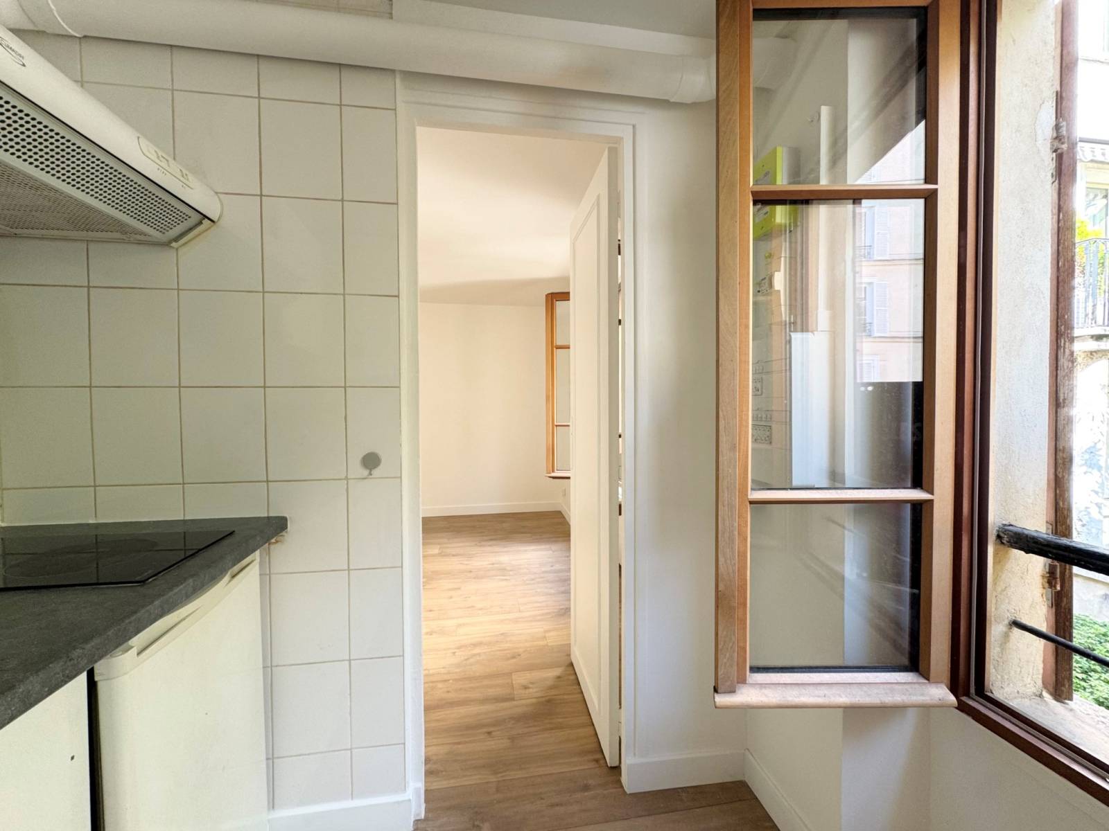 Cuisine indépendante équipée, fonctionnelle et bien agencée, avec fenêtre sur cour arborée