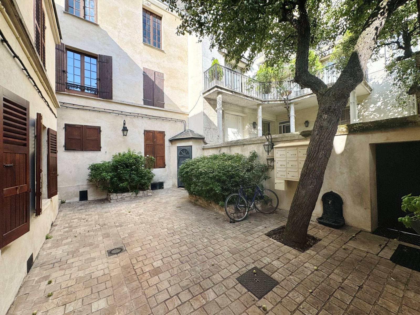 Cour commune pavée, typique des petits immeubles parisiens, offrant un cadre serein et charmant