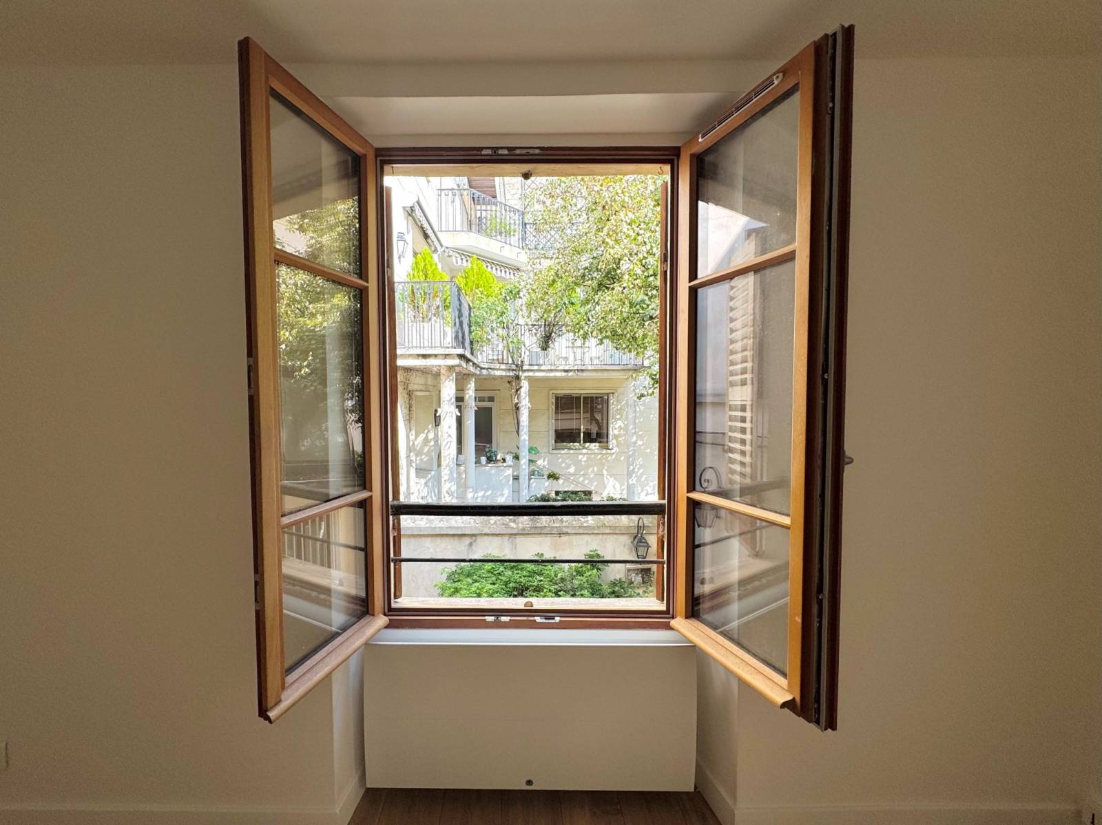 Vue directe depuis la fenêtre du séjour sur une belle cour arborée, sans vis-à-vis gênant