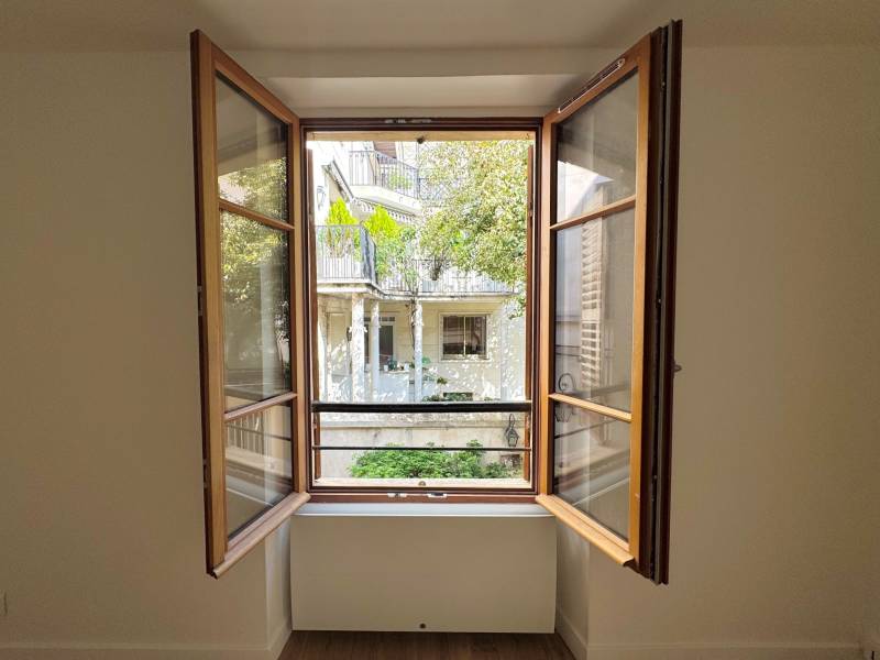 Vue directe depuis la fenêtre du séjour sur une belle cour arborée, sans vis-à-vis gênant